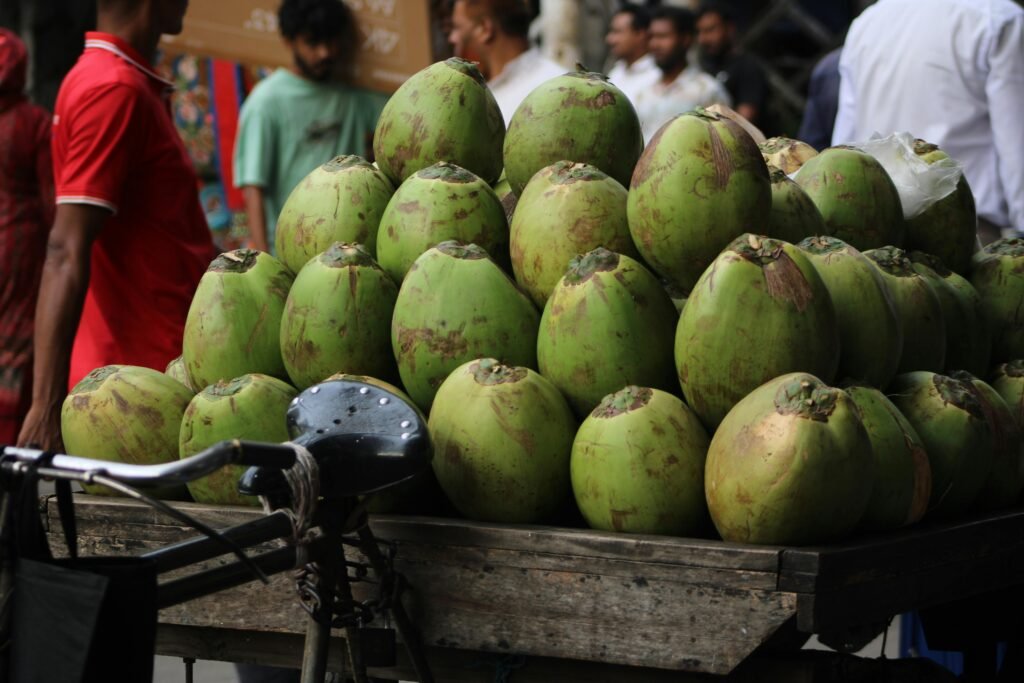 Vibrant fresh coconuts stacked on a street vendor cart, bustling with activity.